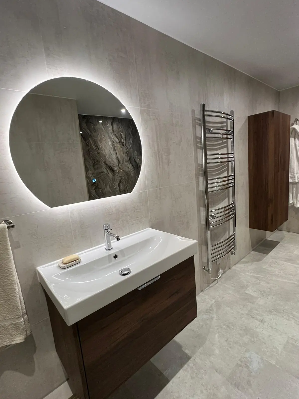 Spacious bathroom with wood furniture and marble-effect finishes