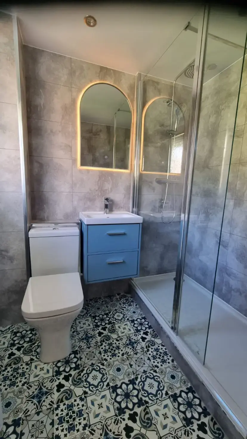 Compact shower room with blue vanity and patterned floor